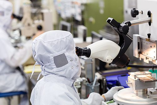 Scientist in cleanroom using microscope